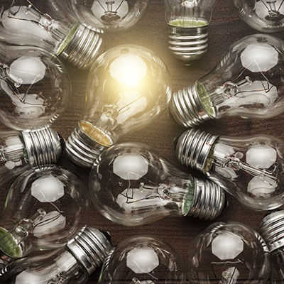 Group of light bulbs with one lit up to show unique attributes.